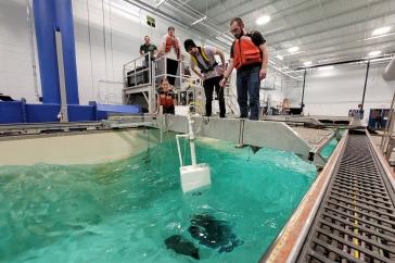 Students wearing life vests st和 at the edge of a test tank